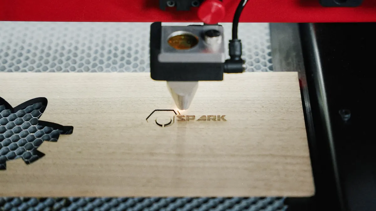 CO₂ laser engraving the Spark logo into wood